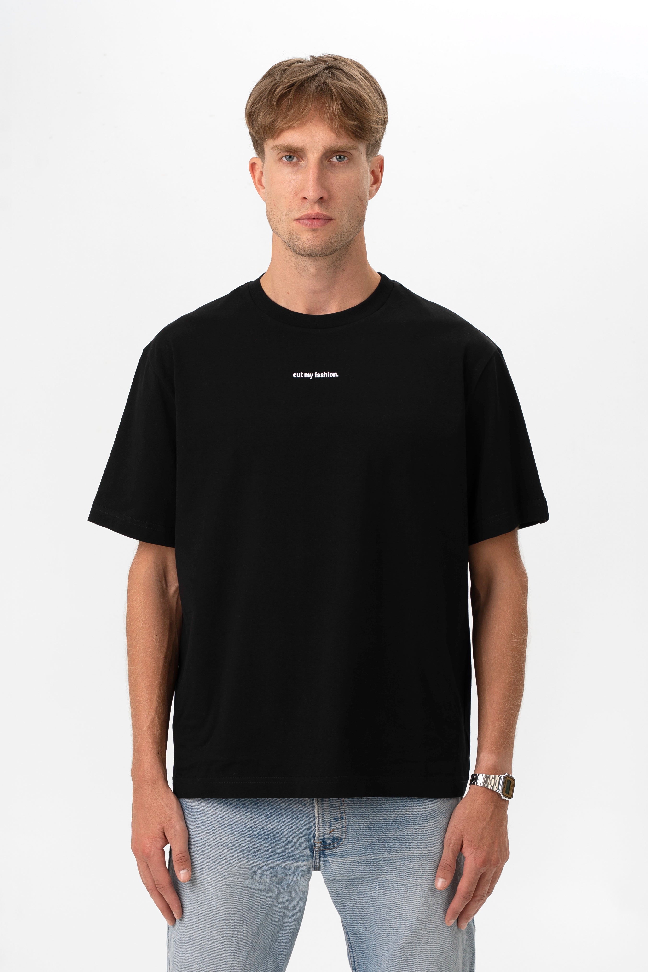 Priekinis vaizdas, kuriame matyti juodi oversized marškinėliai su minimalistiniu baltu logotipu „cut my fashion.“ krūtinės srityje