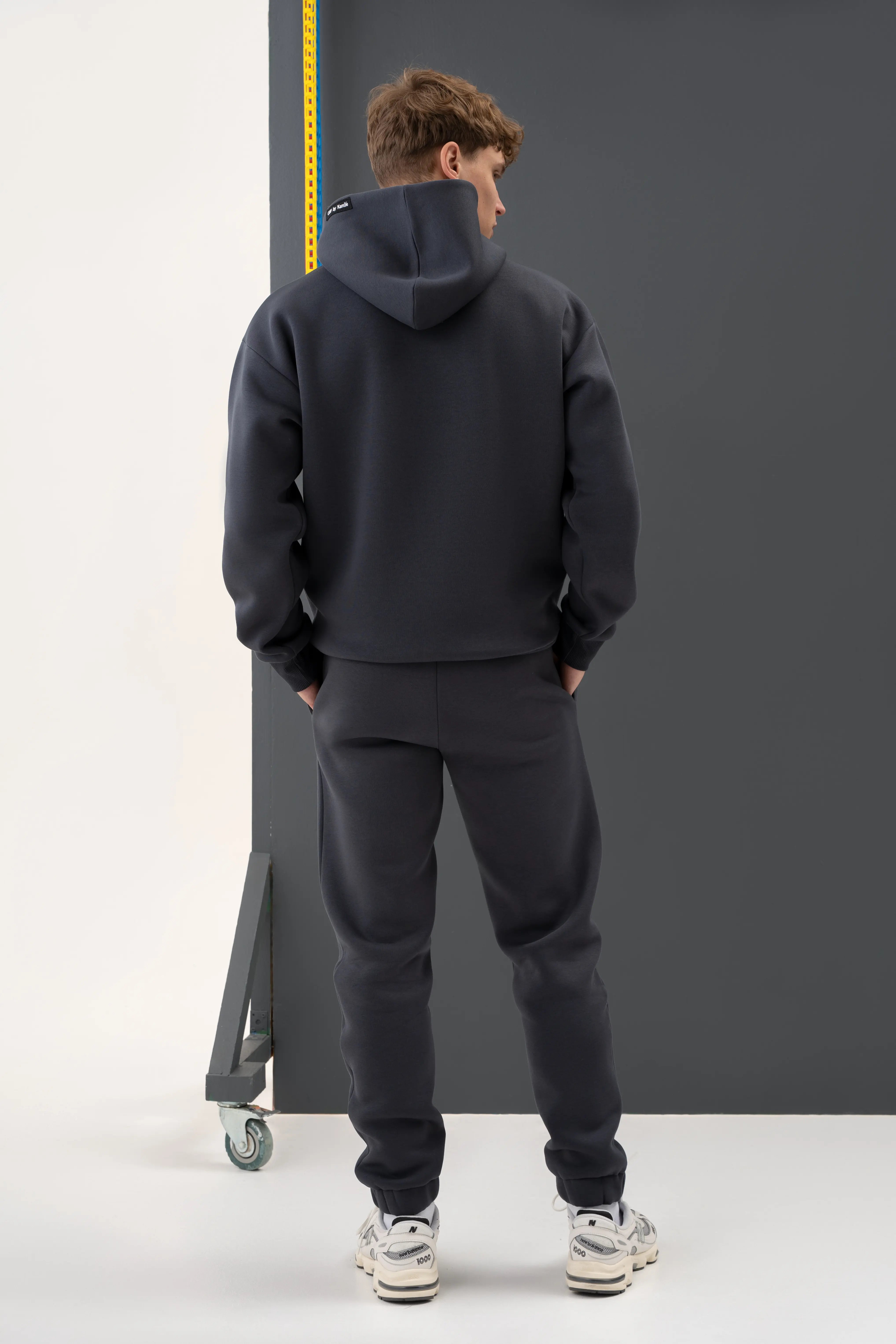 Tamsiai pilkas vyriškas laisvalaikio treningas su kapišonu, sukurtas cutmyfashion siuvykloje Lietuvoje.