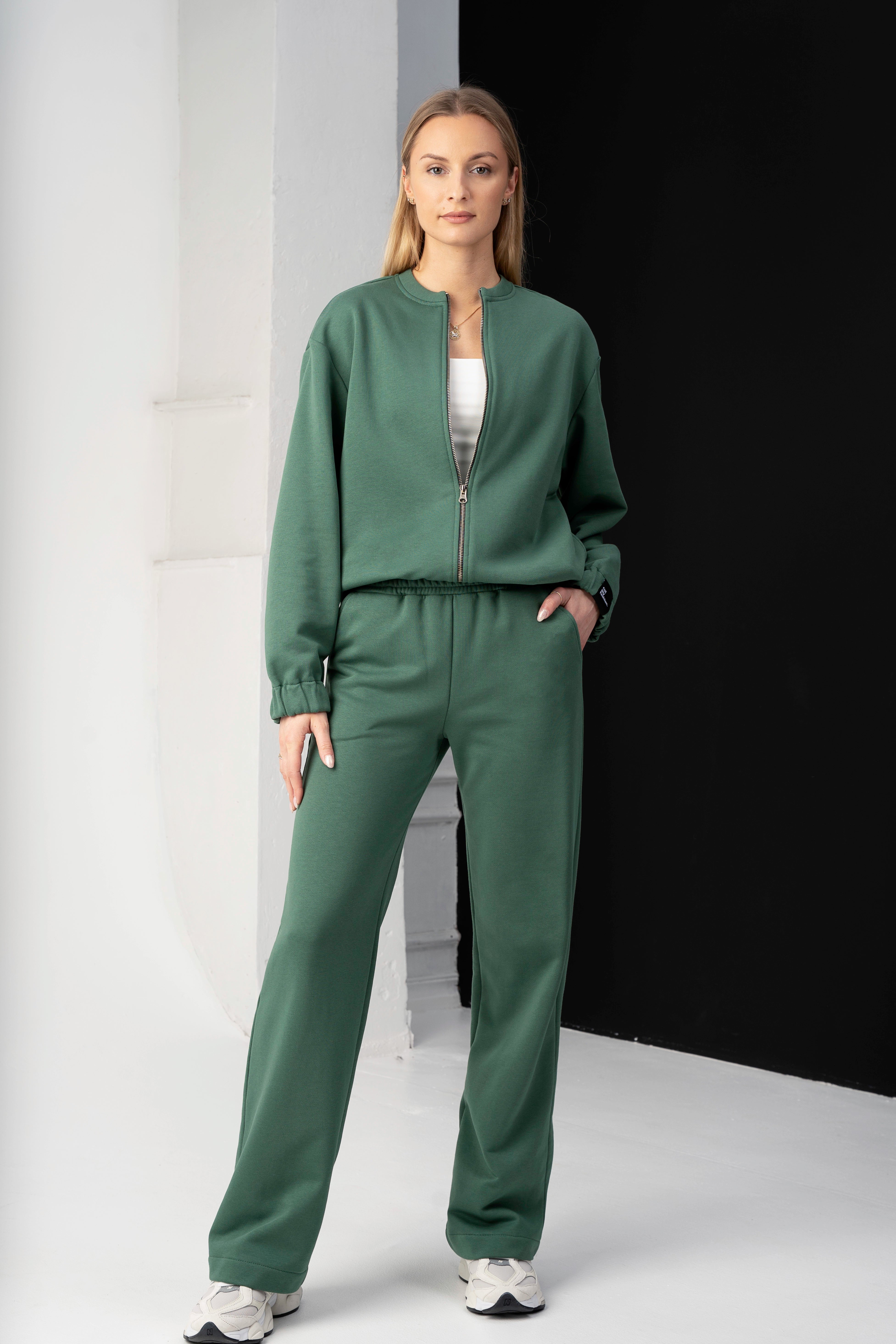 modelis vilki žalius cutmyfashion treningus mėja, pozuoja studijoje žiūrėdama į objektyvą