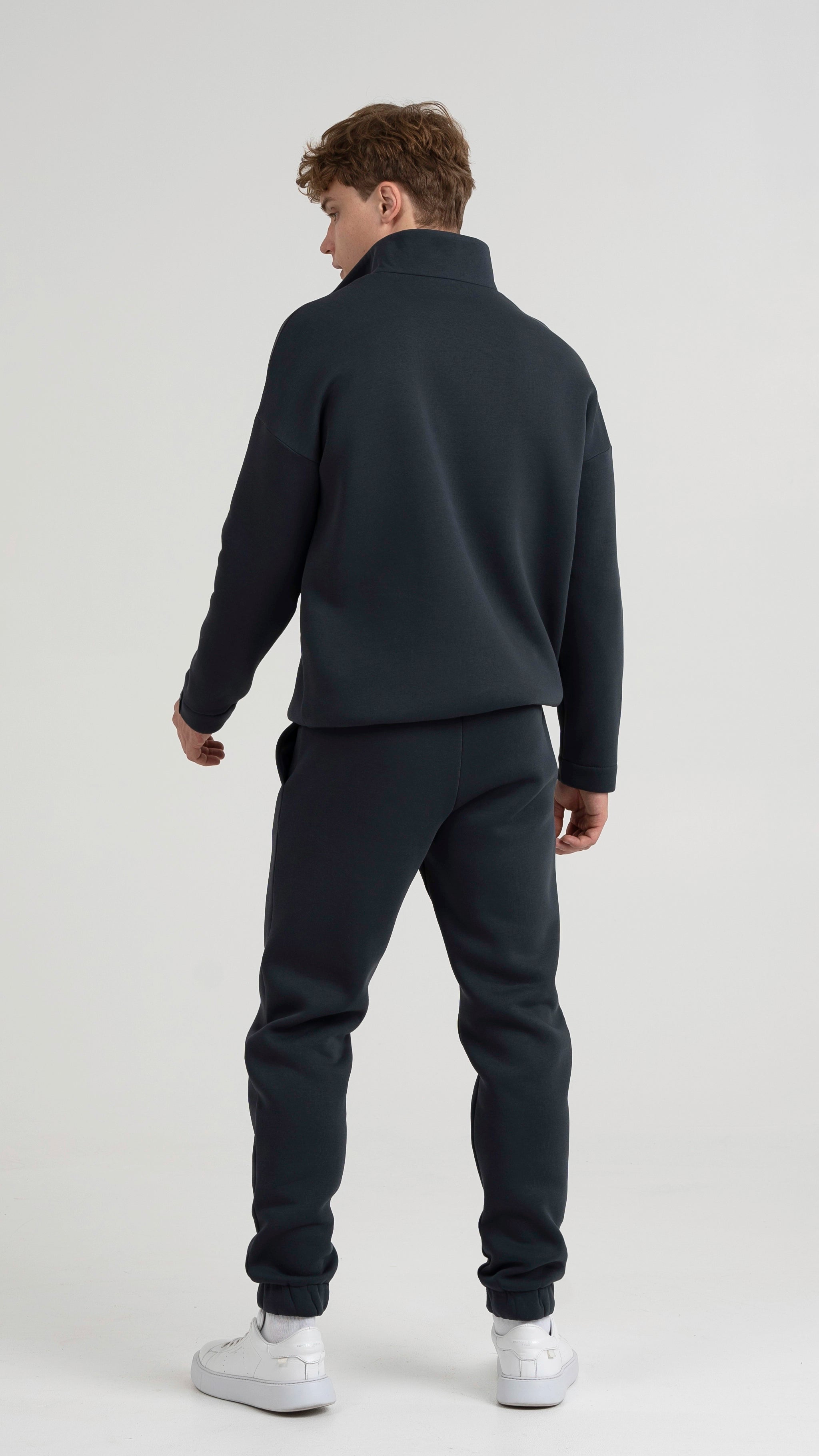 Vyro nugara vilkint tamsiai pilkus treningus, rodoma striukės ir jogerių stiliaus kelnių forma